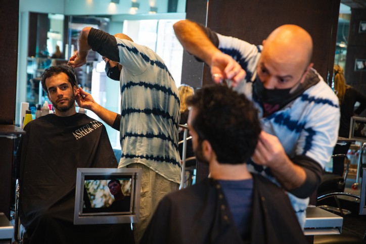 A hairdresser wearing a face mask cuts the hair of a customer at a hair salon in Jerusalem on February 7, 2021 as Israel exits a 3rd lockdown due to the COVID-19 coronavirus pandemic. Photo by Olivier Fitoussi/Flash90 *** Local Caption *** ???????
?????
???
????
??????
?????