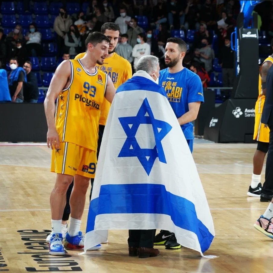 שחקני מכבי תל אביב יחד עם הבעלים שמעון מזרחי מתעטפים בדגלי ישראל. צילום: מכבי תל אביב