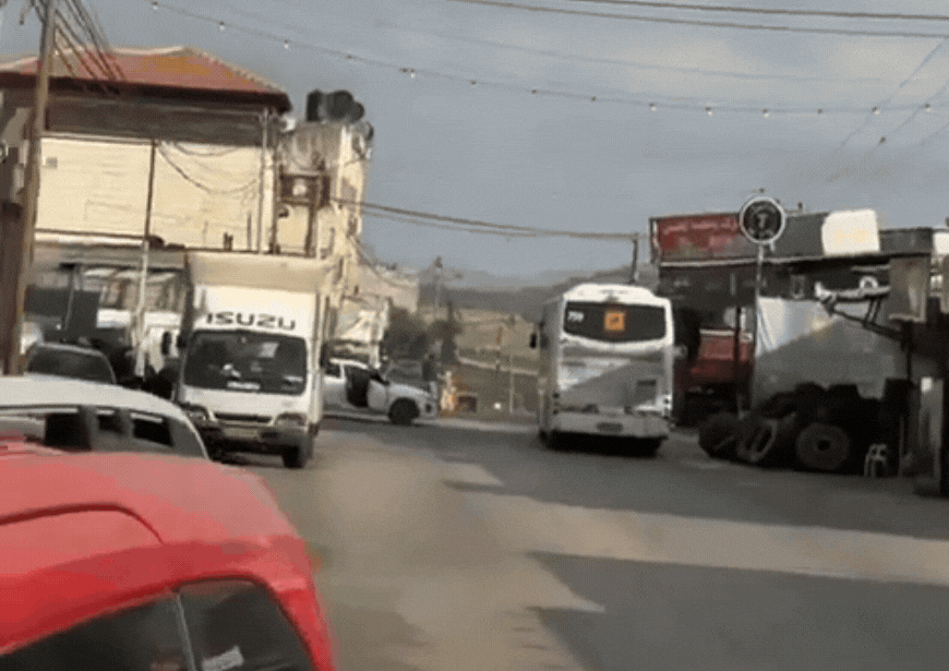 האוטובוס נוסע בכביש, המחבלים יוצאים מהרכב ויורים לעברו