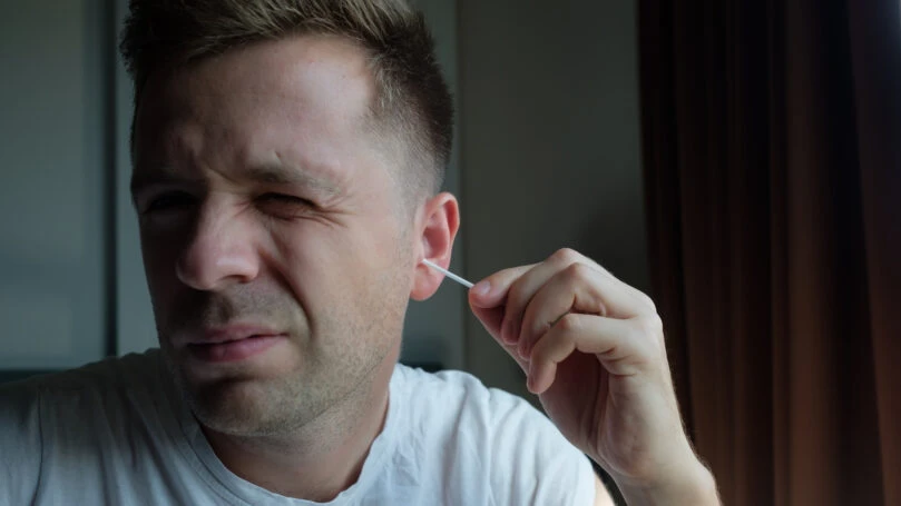 Close up shot of caucasian man cleaning his ears with