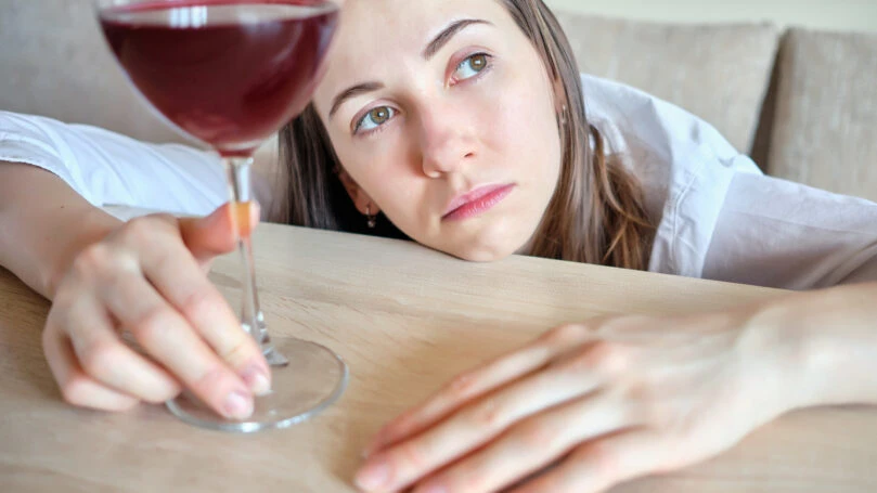 Girl is sad with a glass of wine at the table